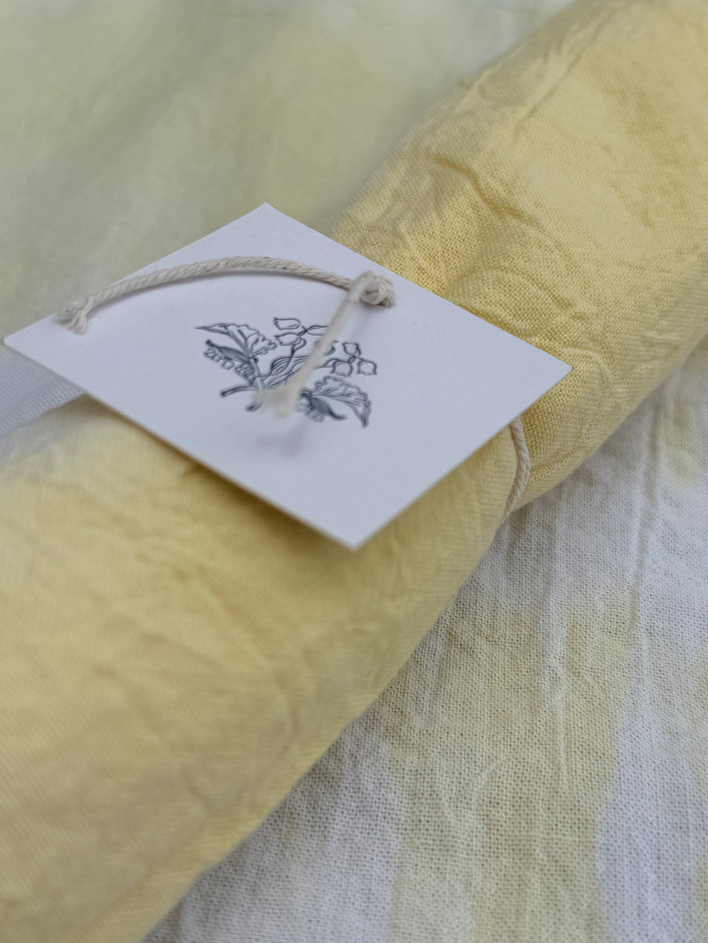 Yellow fabric with a tag featuring leaf designs on a textured surface