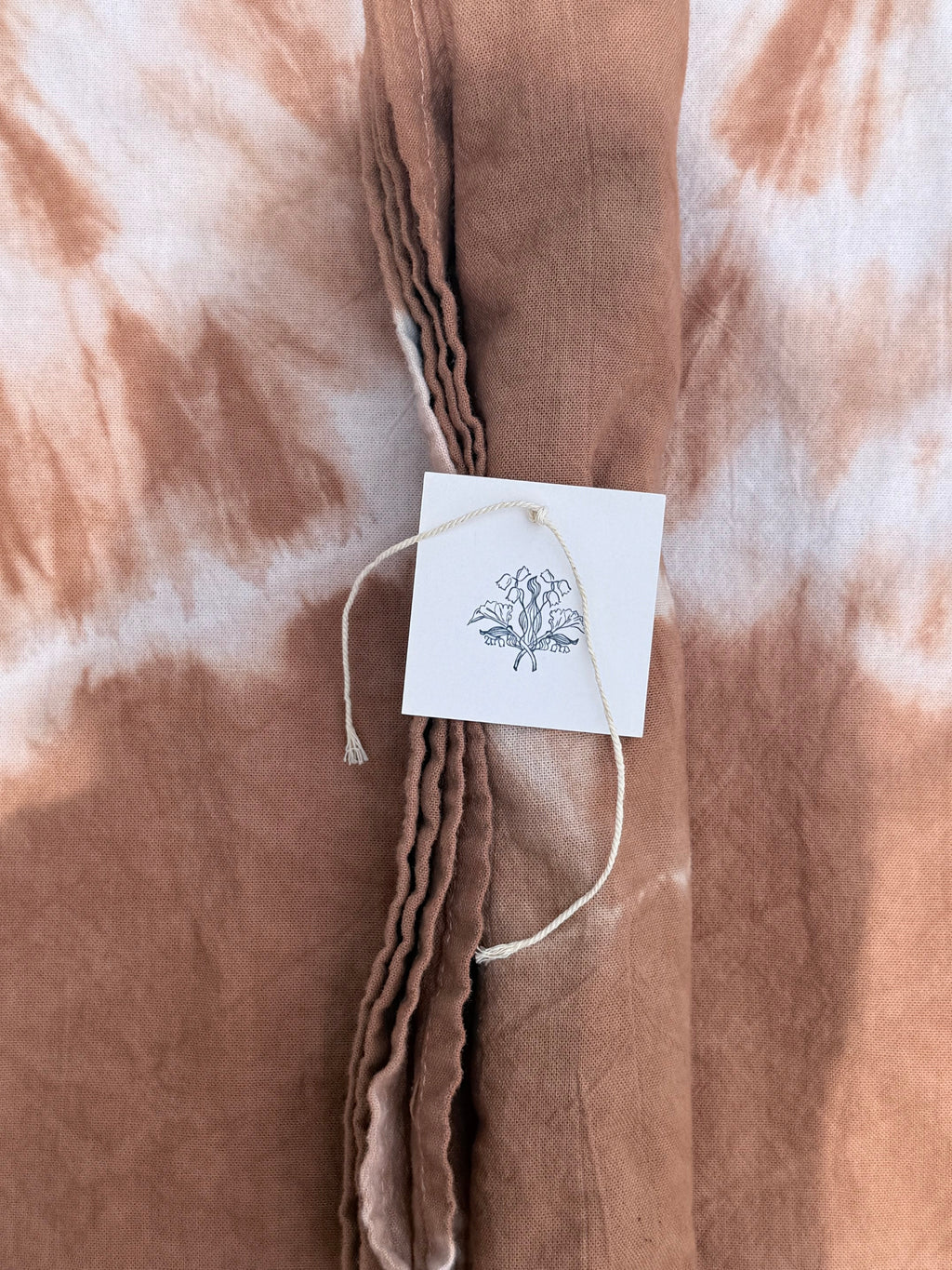 Brown tie-dye fabric with a tag featuring a butterfly design.