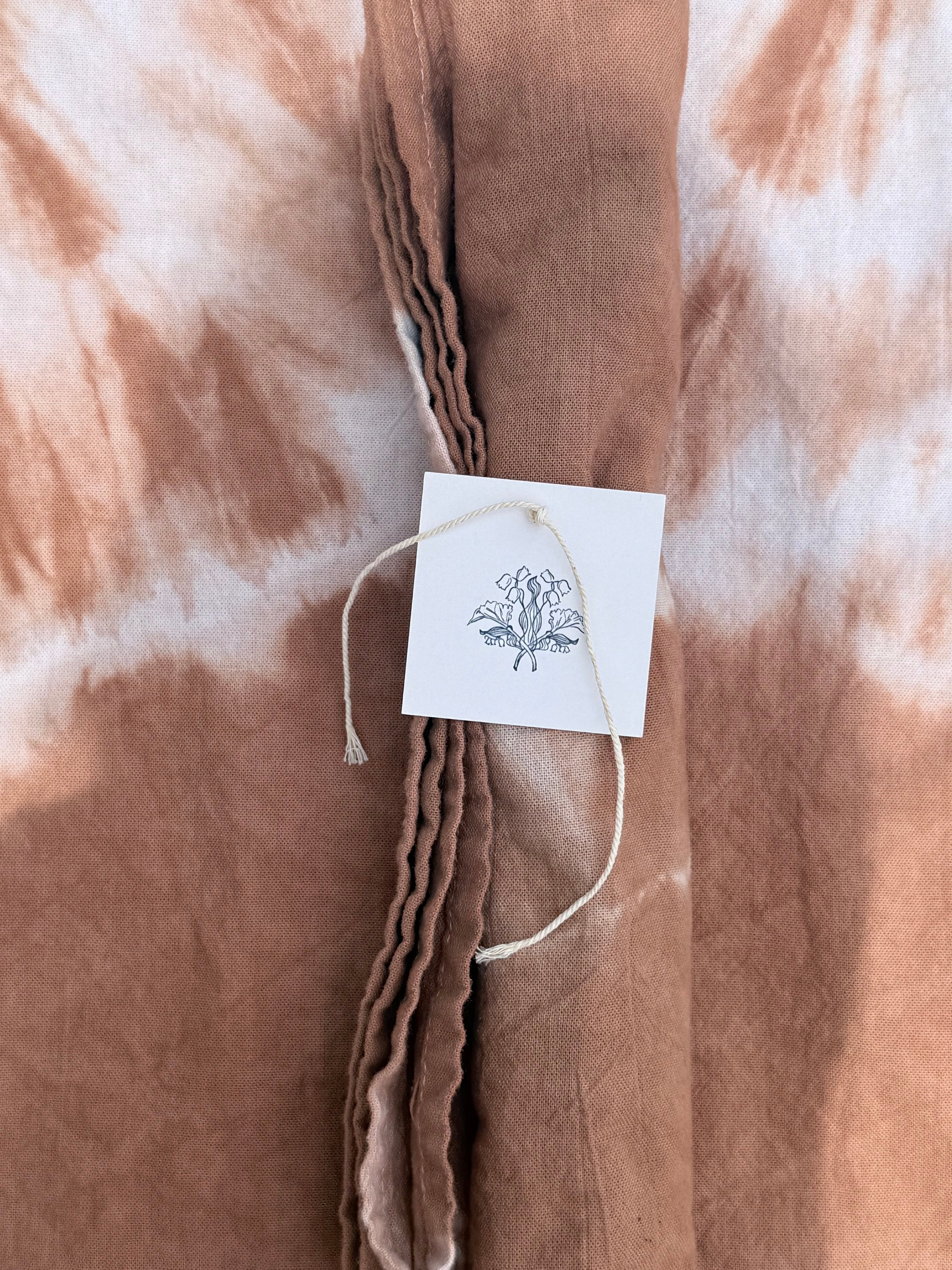 Brown tie-dye fabric with a tag featuring a butterfly design.